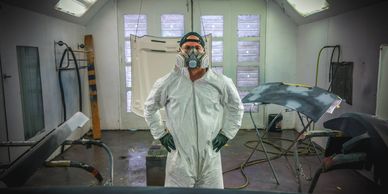 man standing in a paint booth wearing a respirator